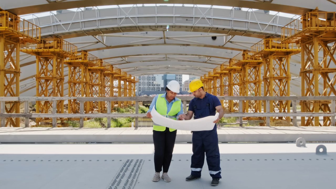 Dois profissionais analisam uma planta técnica em uma obra