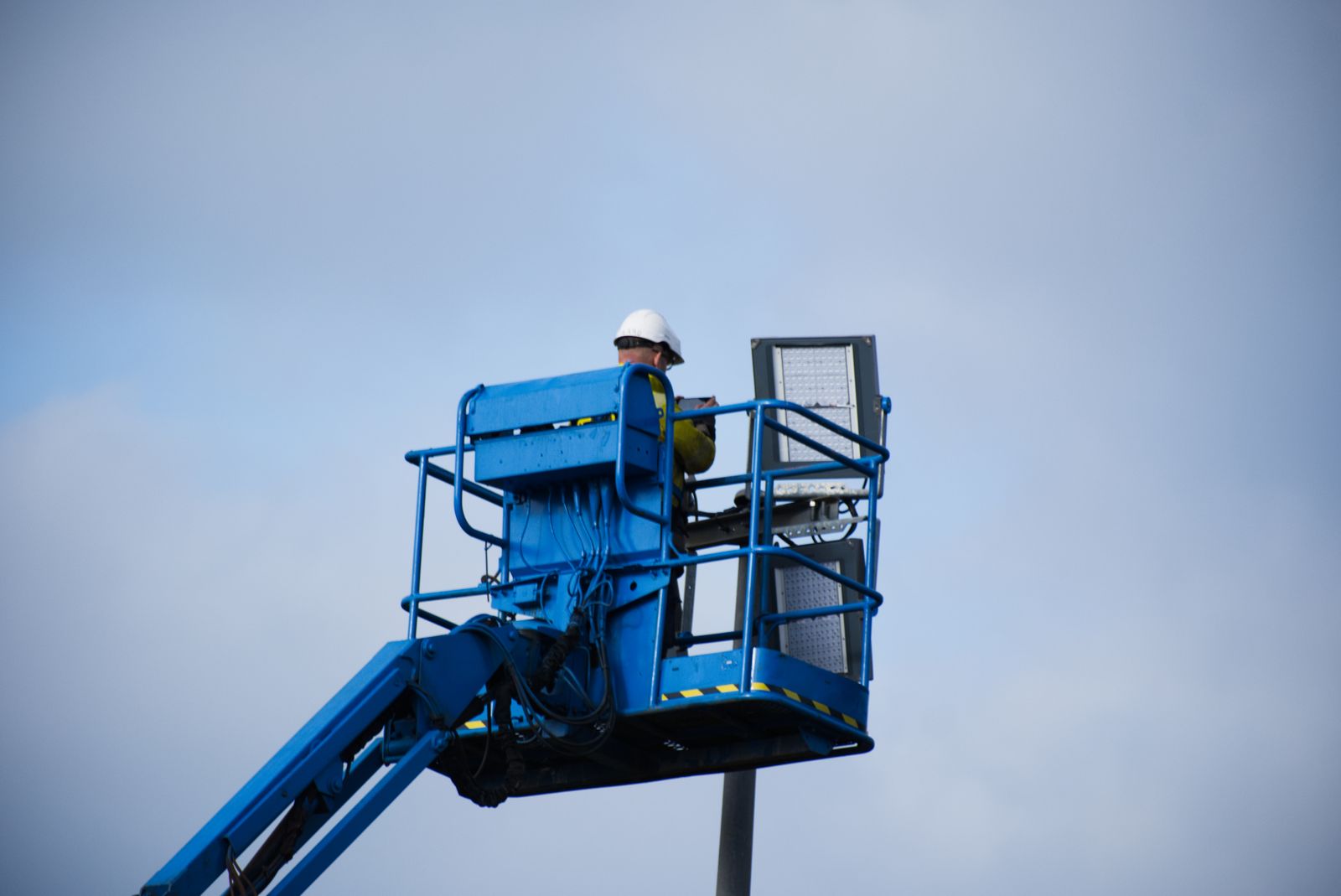Profissional utilizando uma plataforma elevatória em uma atividade técnica de campo