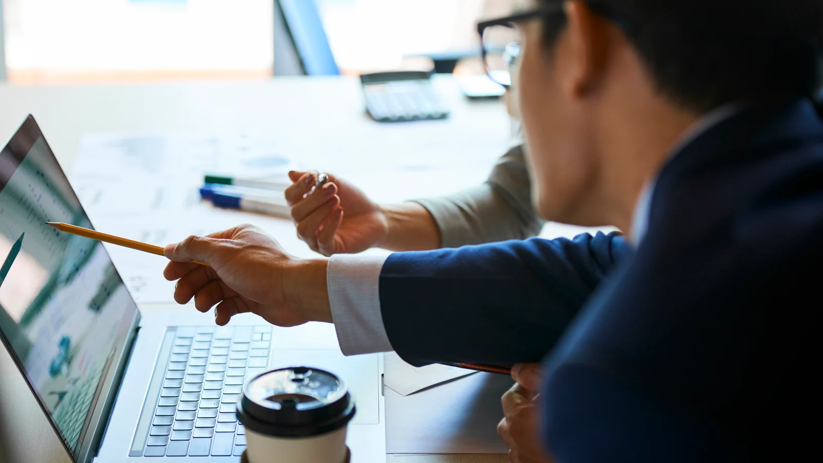 Profissionais analisando dados financeiros em um notebook durante uma reuni&atilde;o